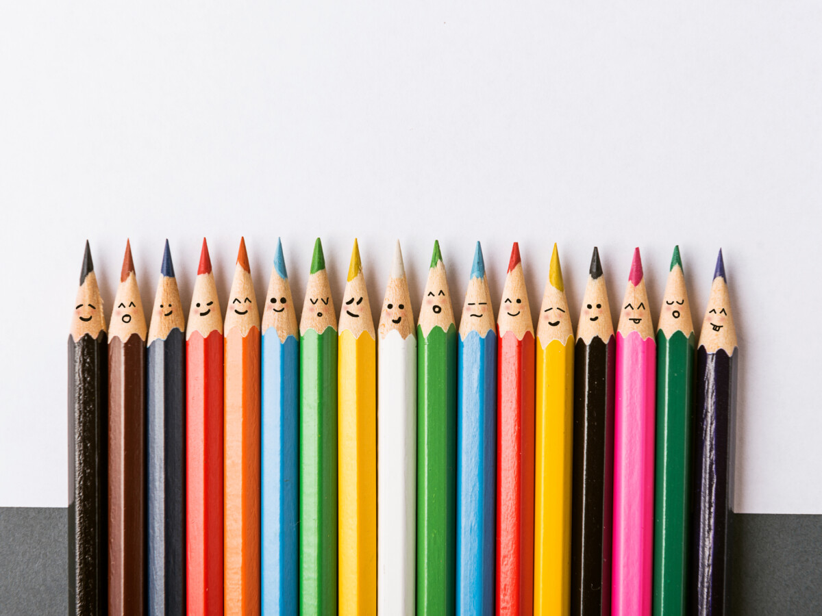 Crayons de couleur avec des smileys, représentant la diversité.