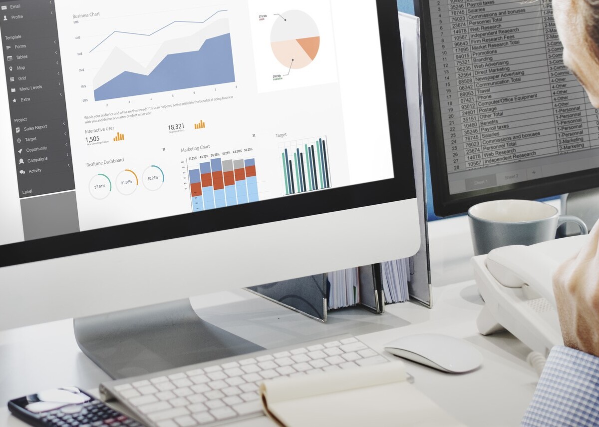 Telefonierender Mitarbeiter vor Monitor mit Charts