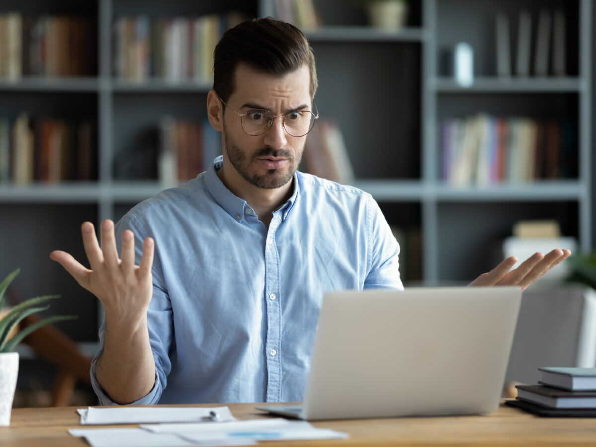 Un homme assis devant son ordinateur portable, perplexe